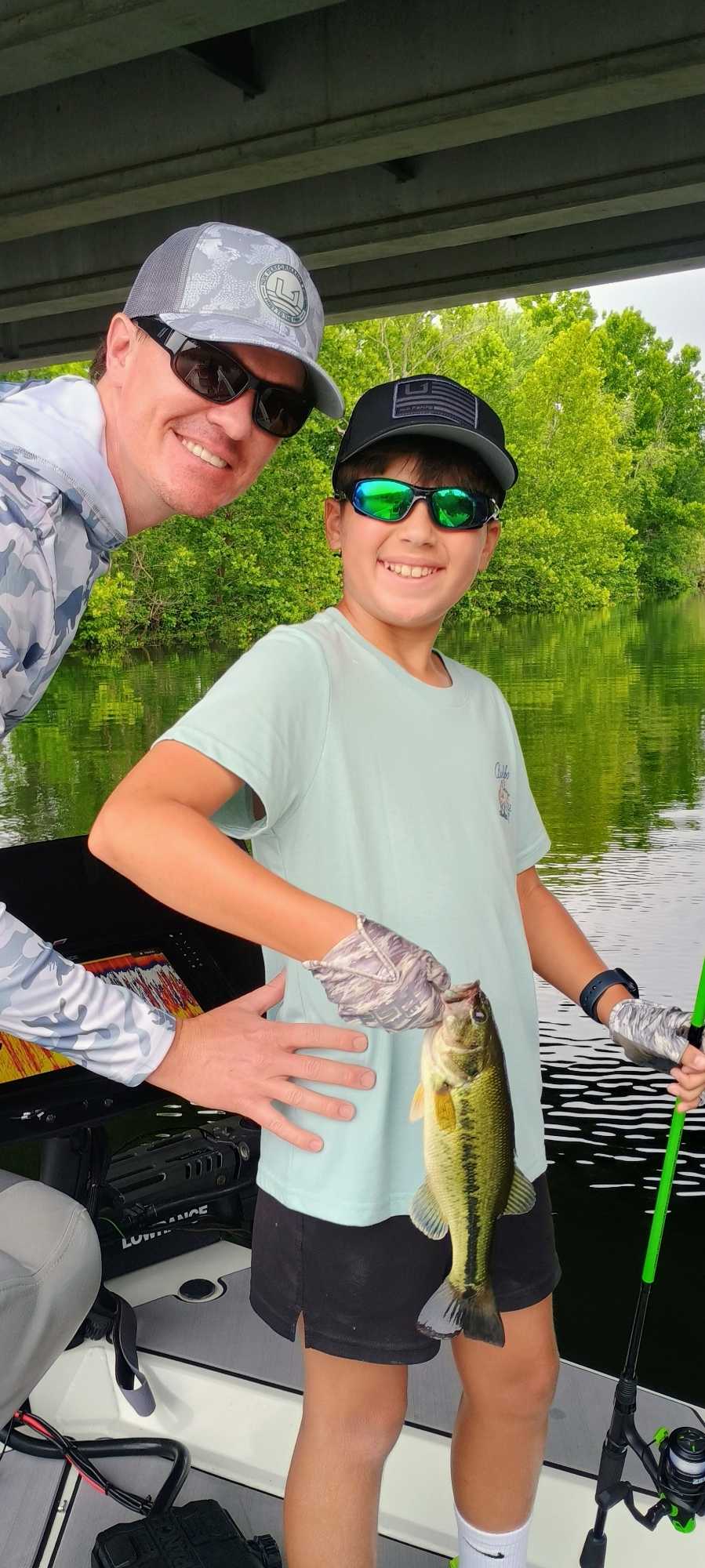 Fishing guide and angler with freshly caught bass on boat in Branson MO