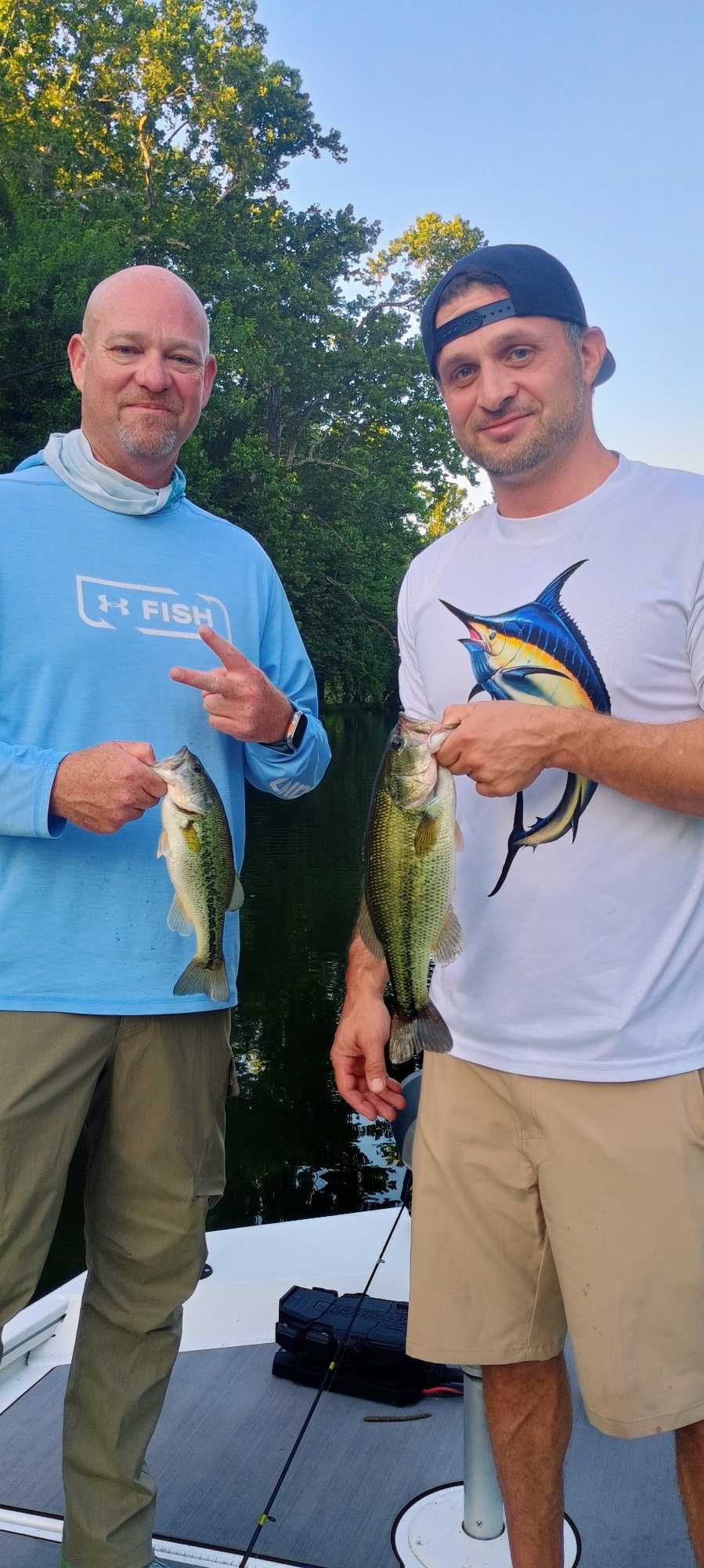 Two anglers displaying freshly caught bass on fishing boat in Branson MO