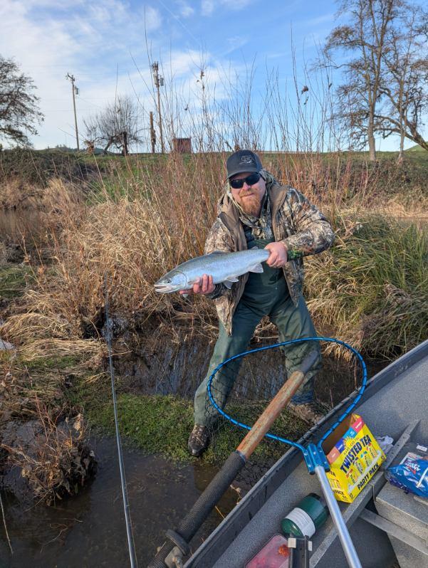 Angler holding freshly caught fish while standing near water in Roseburg OR