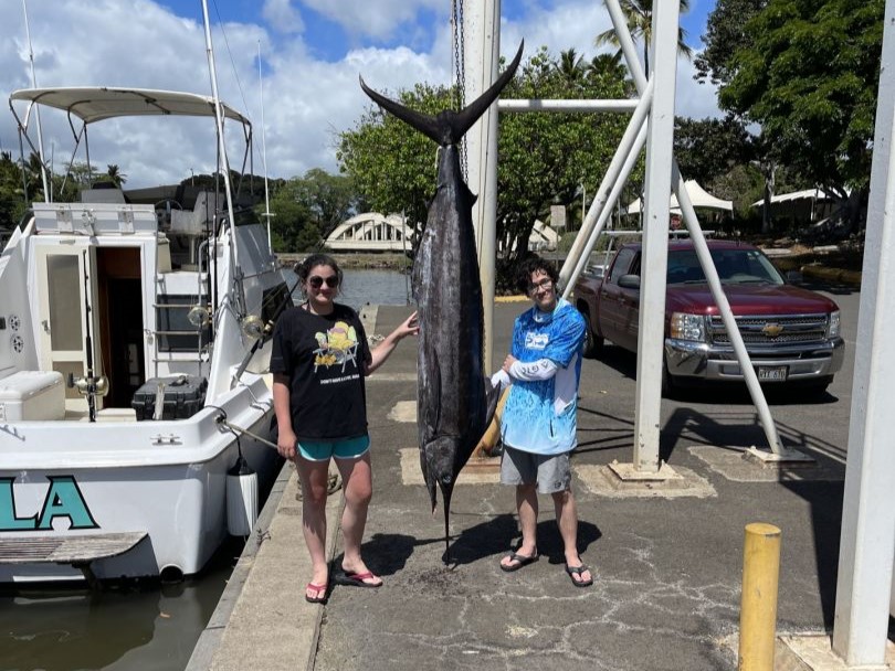 Fisherman holding a large blue marlin caught in Hawaii