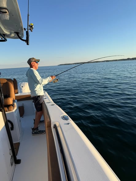 Fishing from boat deck in Wells ME waters with rod extended over calm ocean