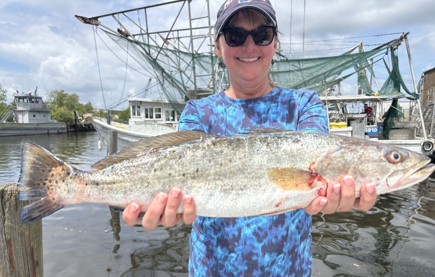 Speckled trout catch displayed at New Orleans LA fishing harbor with shrimp boats in background