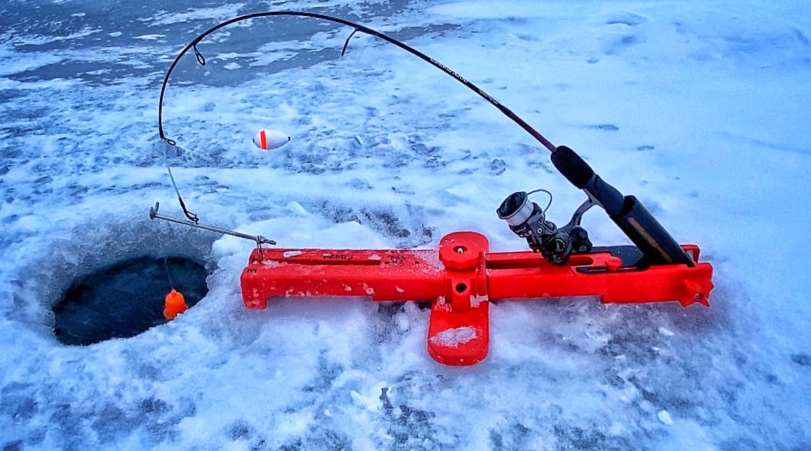 Ice fishing anglers in heated shelter on frozen Wisconsin lake with guide and equipment