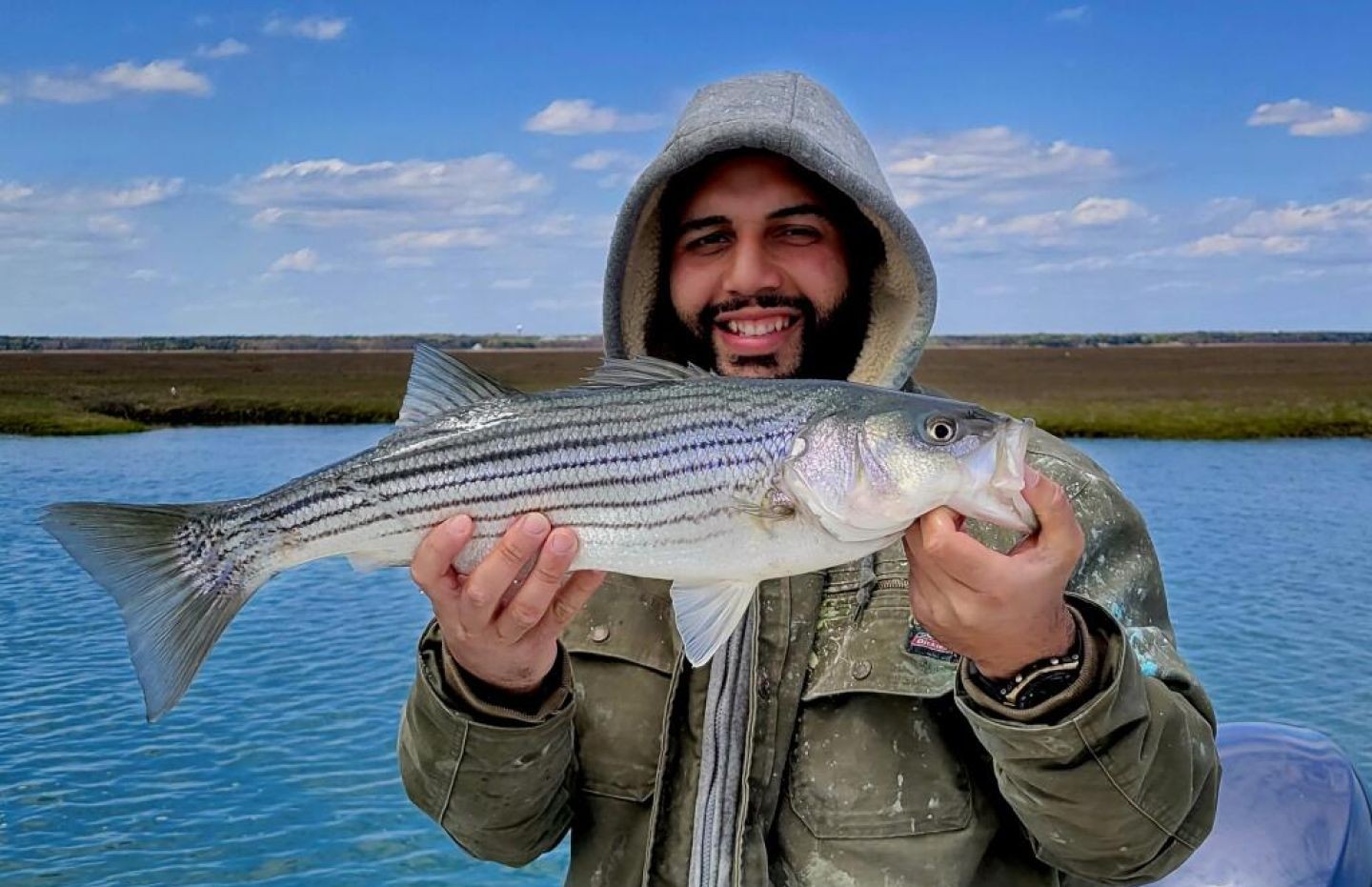 Striped bass catch held over water in Atlantic City NJ fishing trip