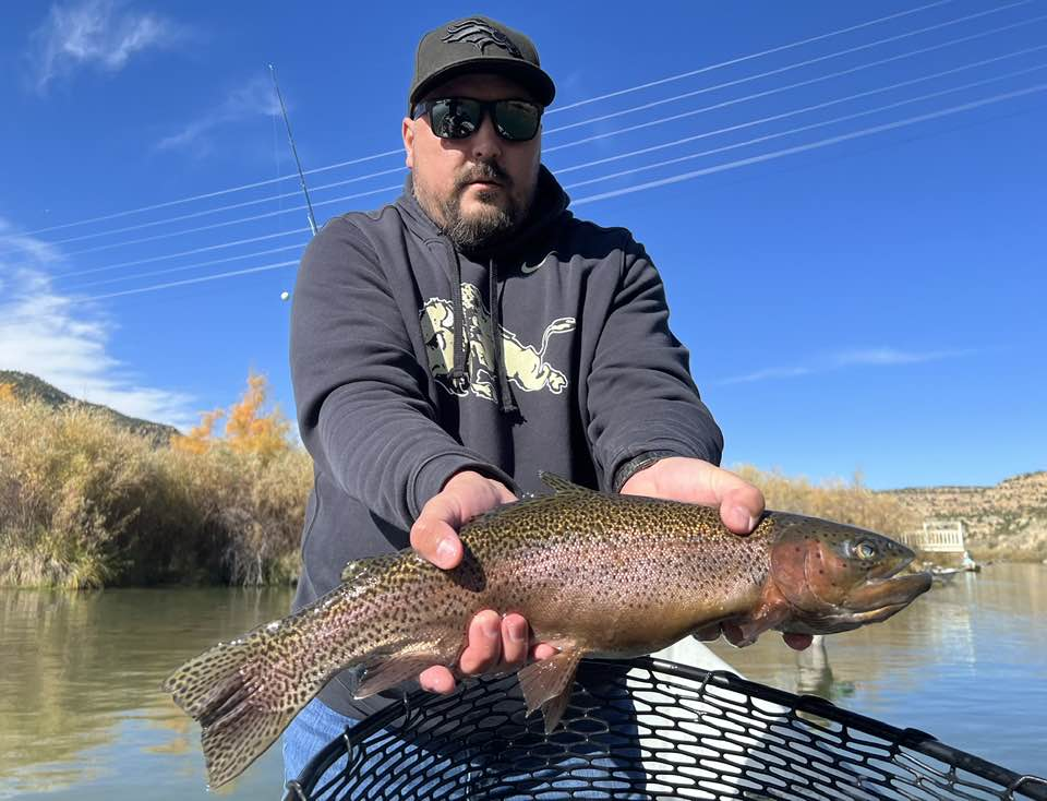 A man holding a large rainbow trout in New Mexico
