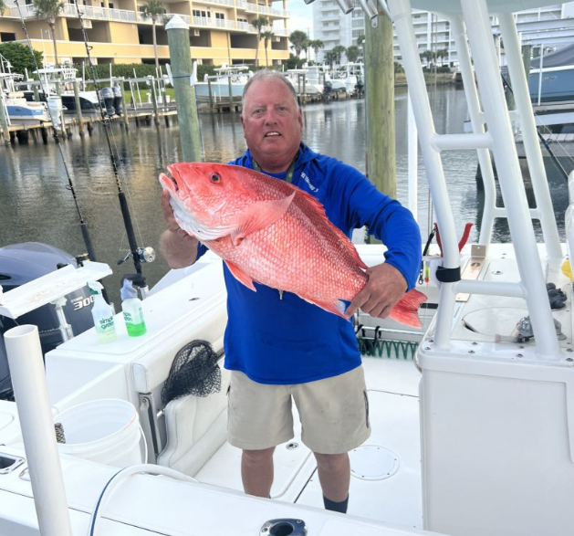 Angler holding a fishing rod against a scenic background in Destin