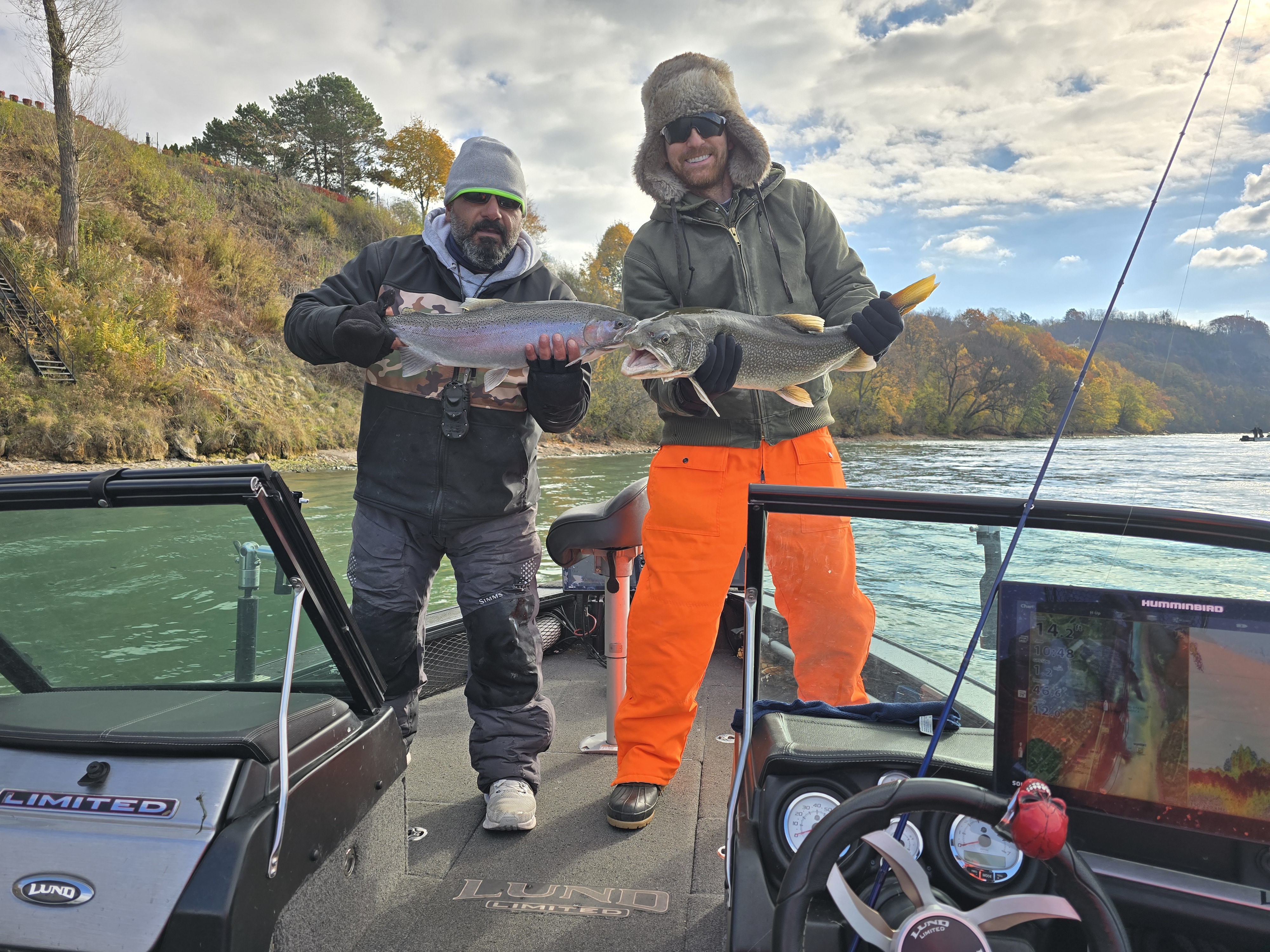 Fishing charter boat on Niagara River with anglers casting lines, Lake Ontario backdrop