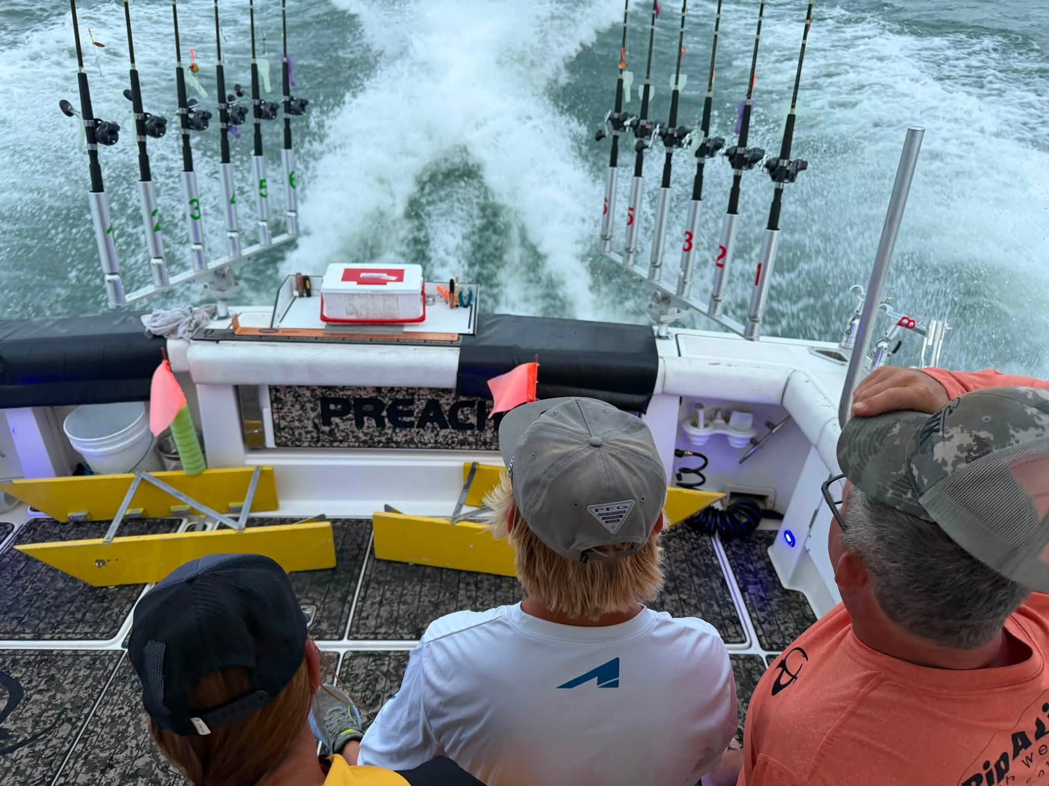 Fishing boat with multiple rod holders and tackle equipment moving through choppy ocean waters