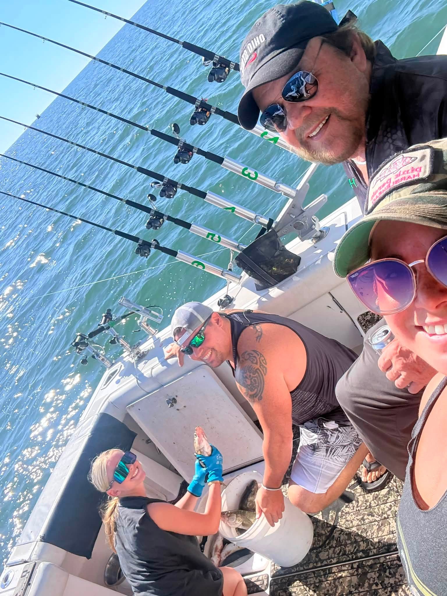 Fishing boat with multiple fishing rods set up over blue ocean water