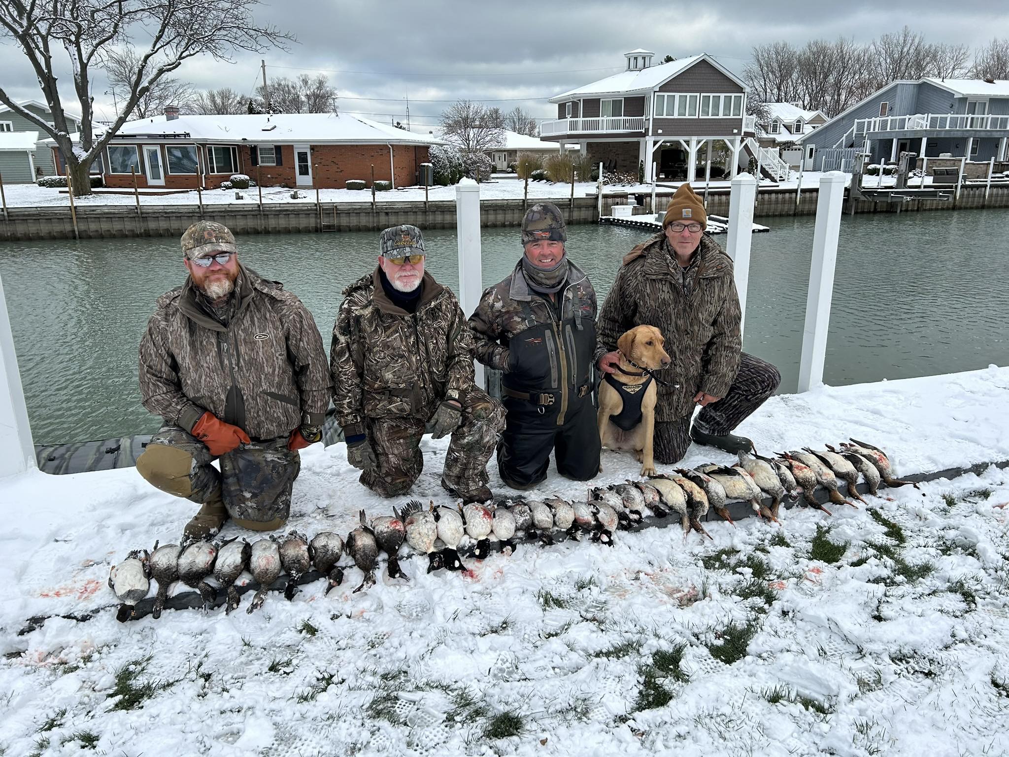 Successful duck hunting trip with harvested waterfowl and hunting dog displayed on snowy dock in Port Clinton OH