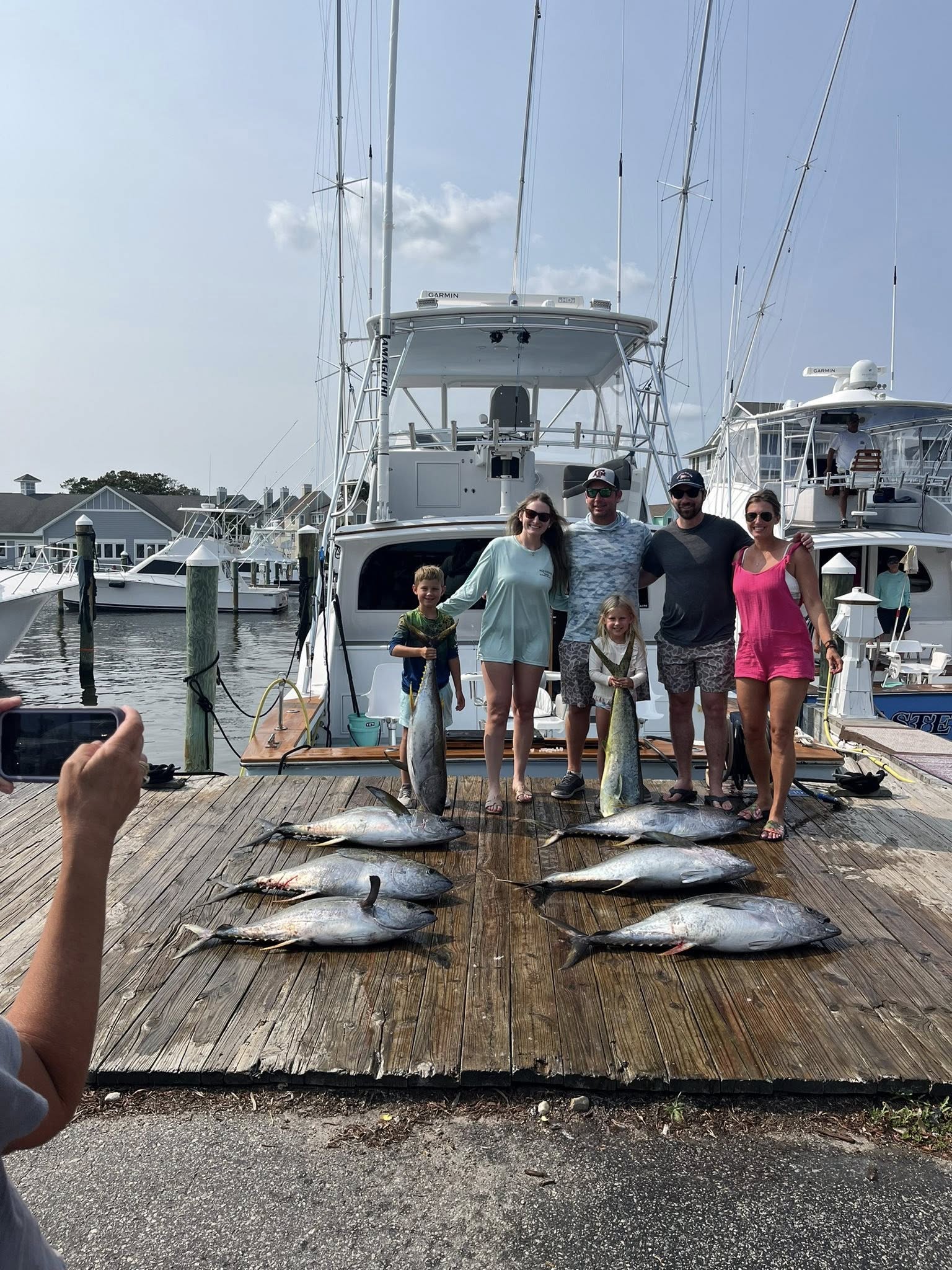 Yellowfin and bluefin tuna catch displayed on dock at Manteo NC marina with fishing boat in background