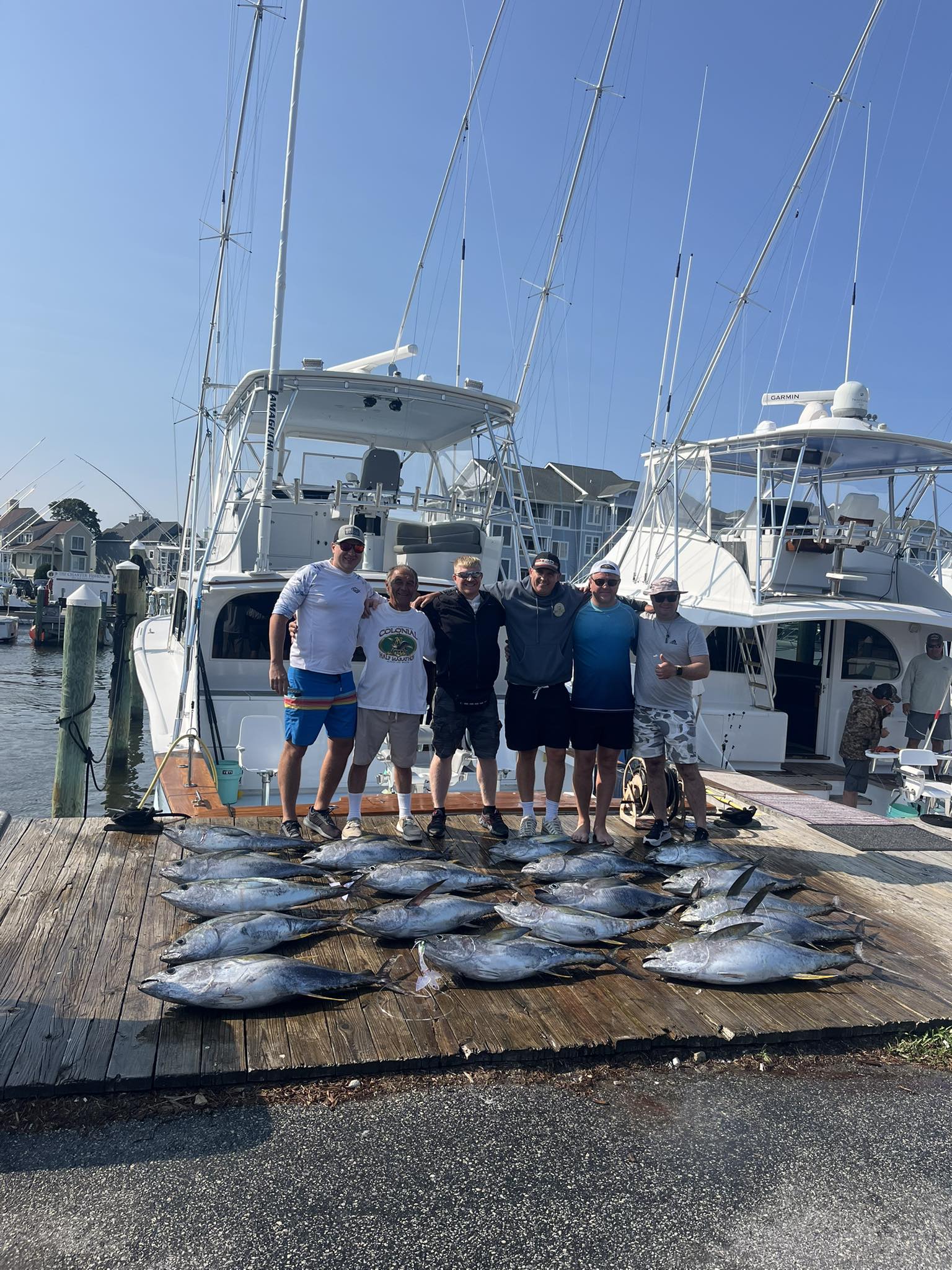 Yellowfin tuna fishing charter catch displayed on dock in Manteo NC with fishing boat and marina in background
