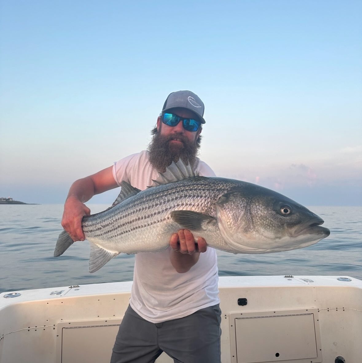 Striped bass fishing charter boat in Wells Maine coastal waters with angler holding fish