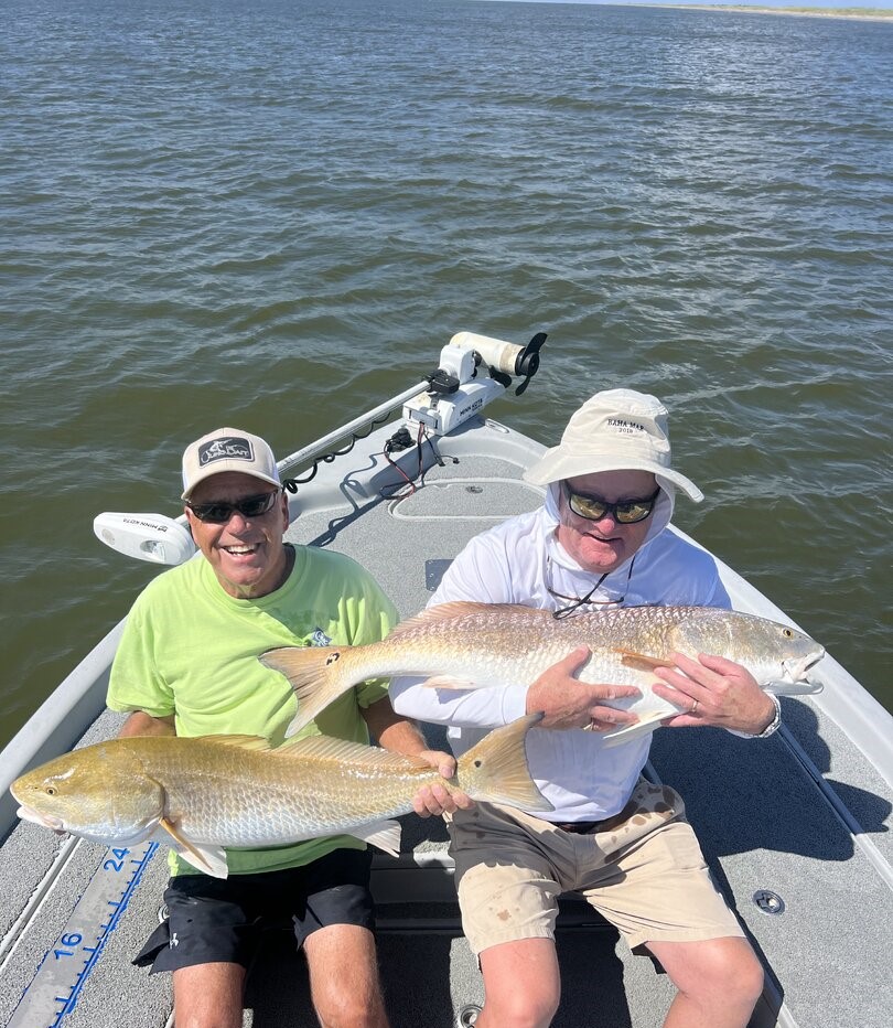 Two anglers displaying caught redfish on fishing boat in Venice Louisiana waters