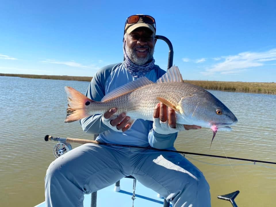 Angler holding caught redfish on fishing boat in Welches OR waters