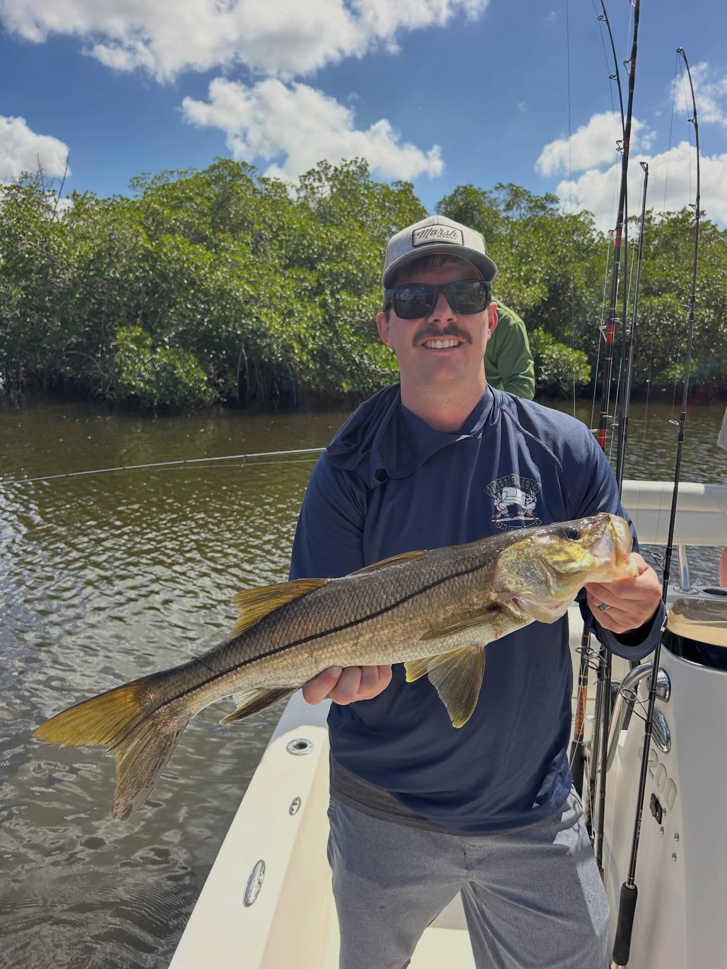 Angler holding freshly caught snook on fishing boat in Fort Myers FL waters