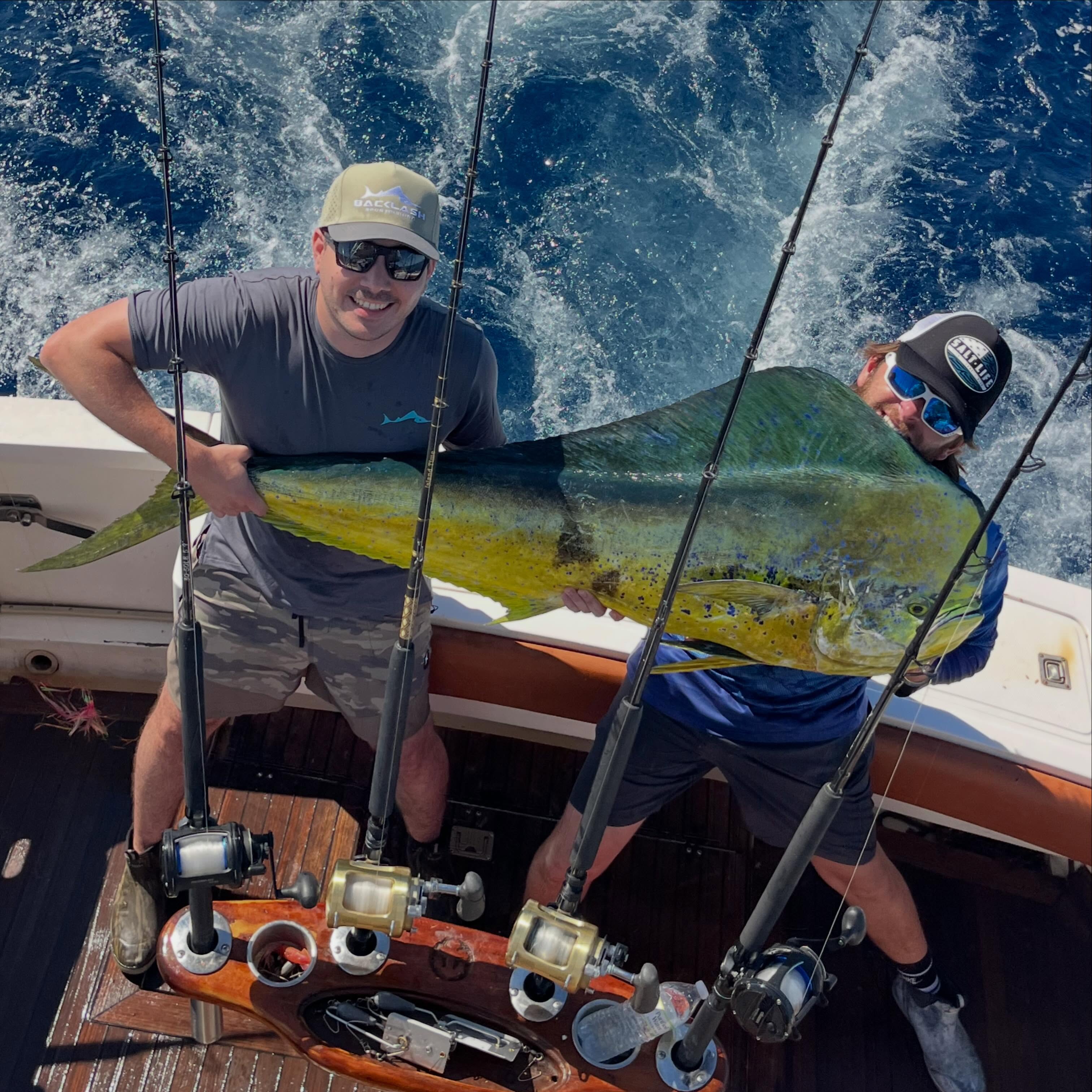 Two anglers holding large mahi mahi fish on fishing boat in Miami FL waters
