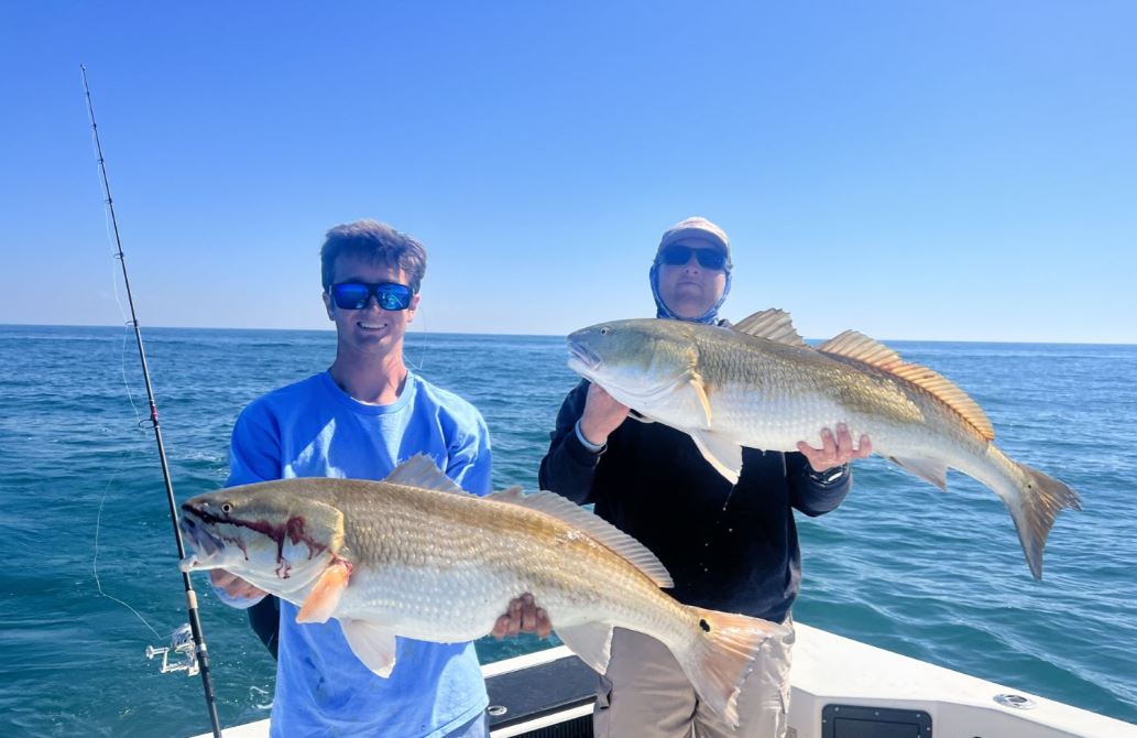 Two anglers holding large fish in Manteo