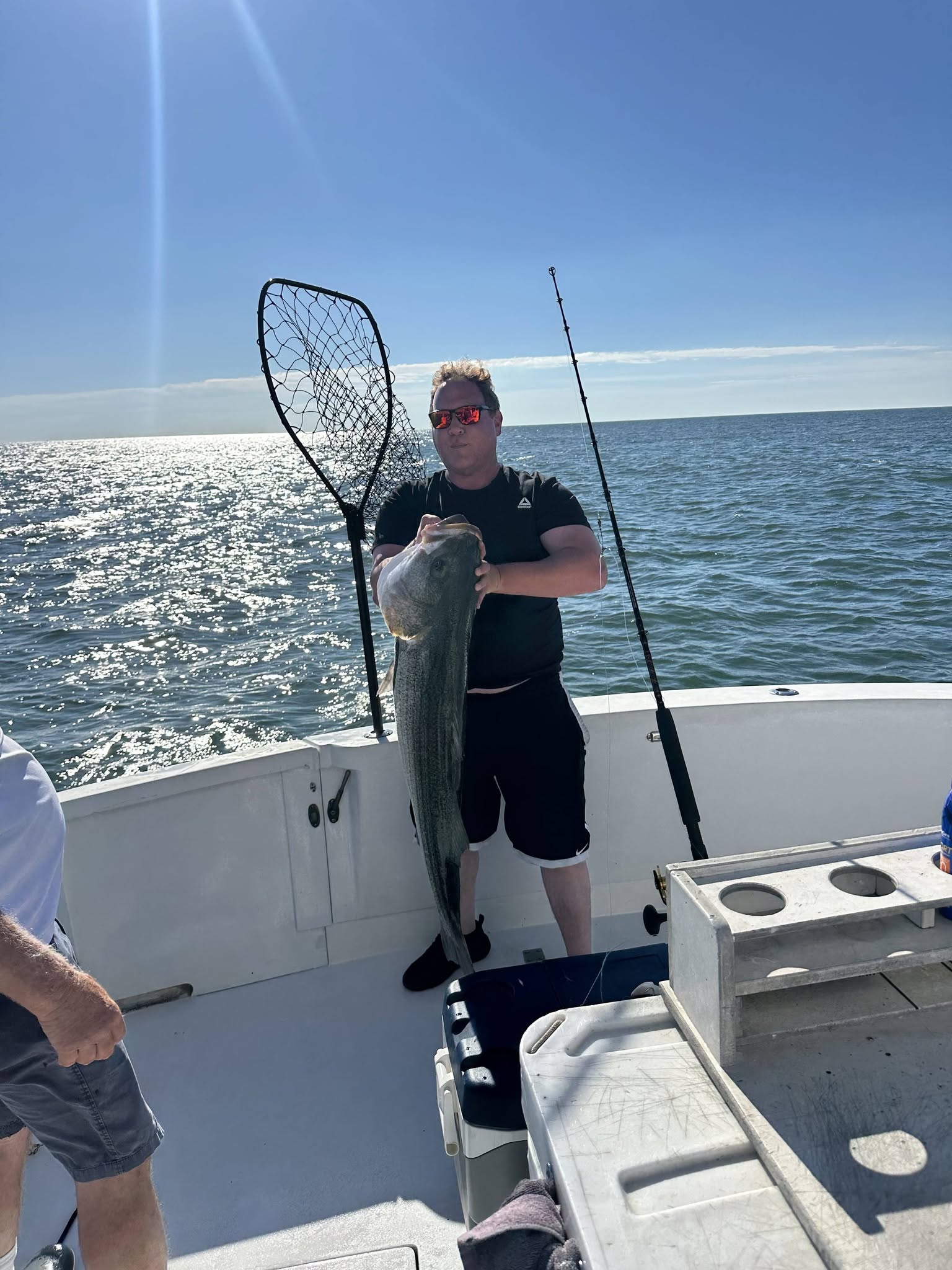 Angler holding caught fish on fishing boat with net in Belmar NJ waters