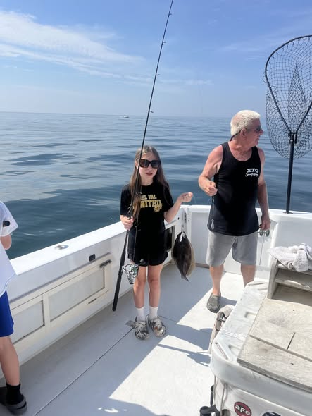 Fishing charter boat on calm ocean waters off Belmar NJ with fishing rods and landing net