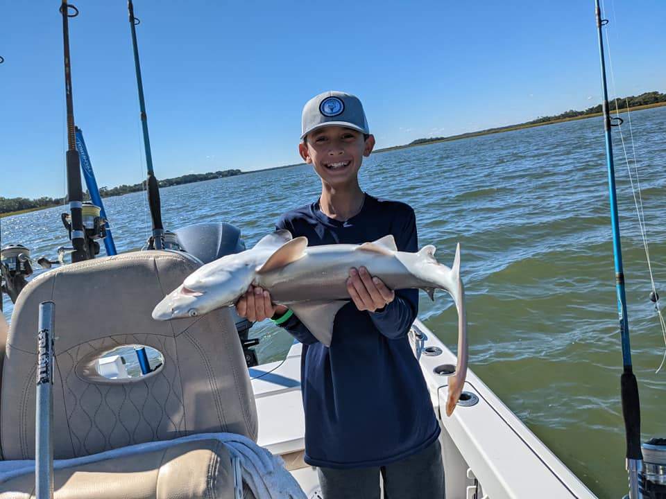 A single fisherman holding a large fish on the beach at Kiawah Island
