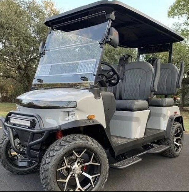 White golf cart with black canopy and custom wheels parked outdoors for tours