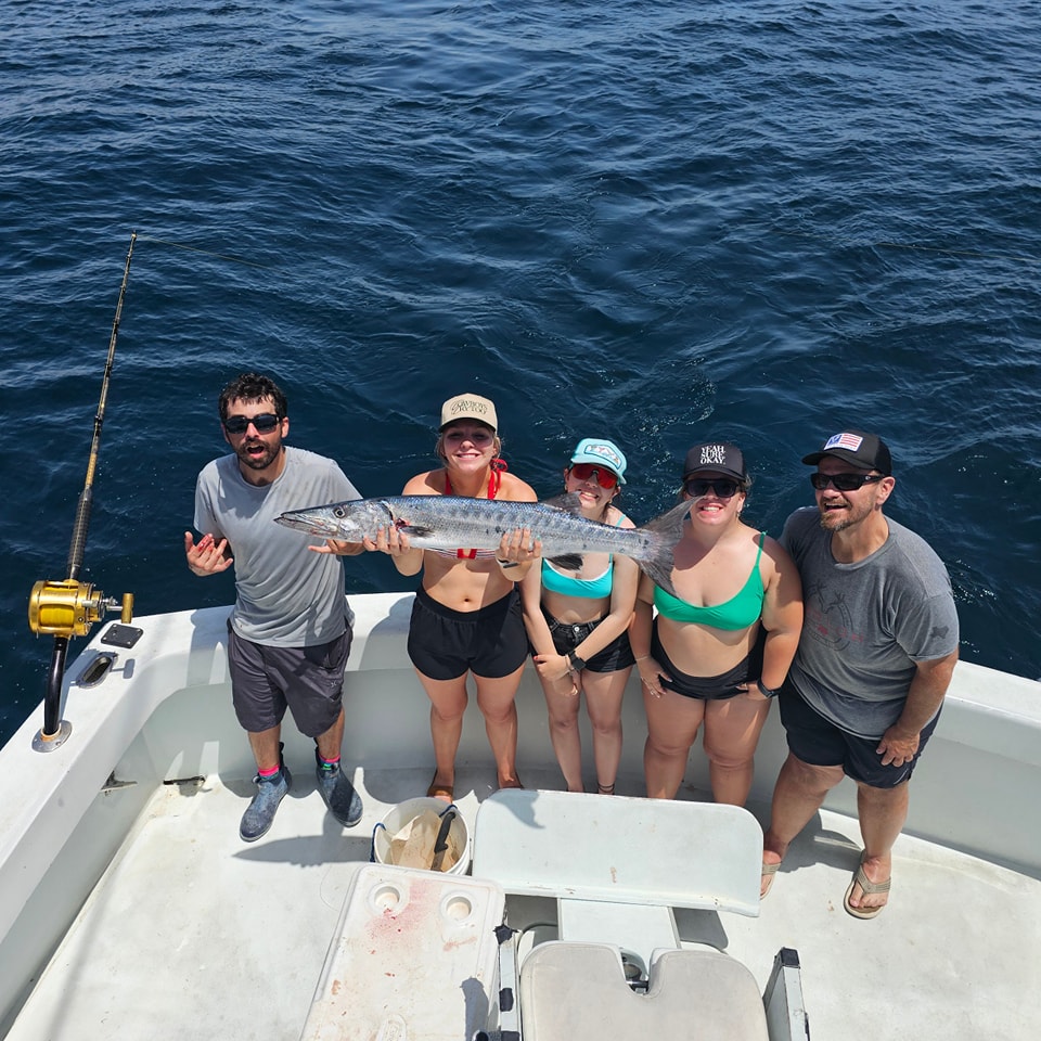 A group of people fishing in Florida, with a great barracuda fish caught.