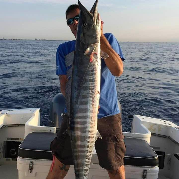 A fisherman holding a large wahoo fish in FL