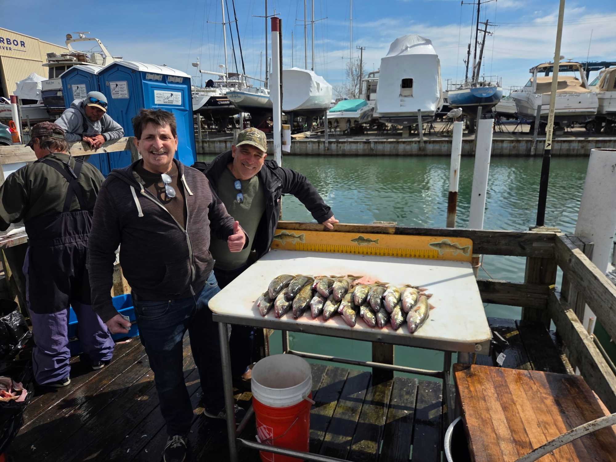 Fishing charter displaying catch of multiple fish on cleaning table at Detroit marina