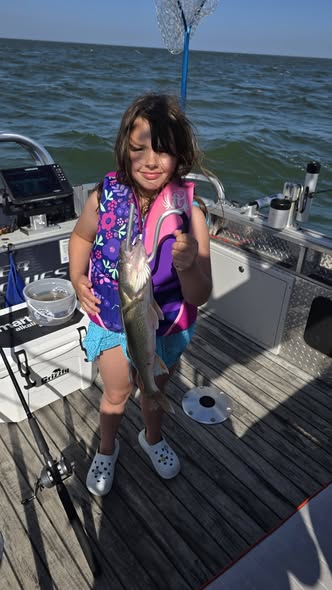Young angler holding caught fish on boat deck in Whitehall MI