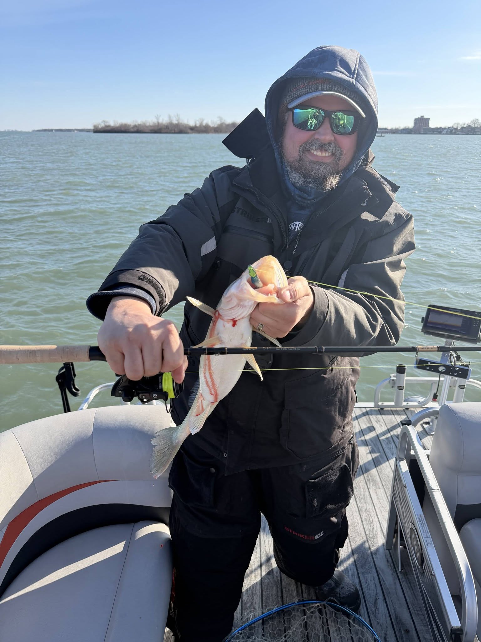 Angler holding freshly caught fish on boat in Whitehall MI waters