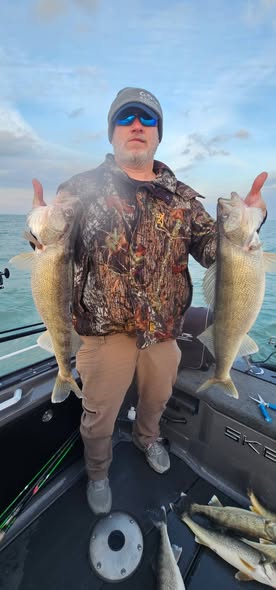 Angler holding two walleye fish on boat in Vermilion OH