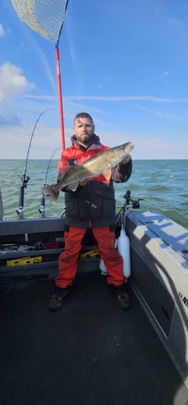 Angler holding caught fish on fishing boat in Vermilion OH with landing net