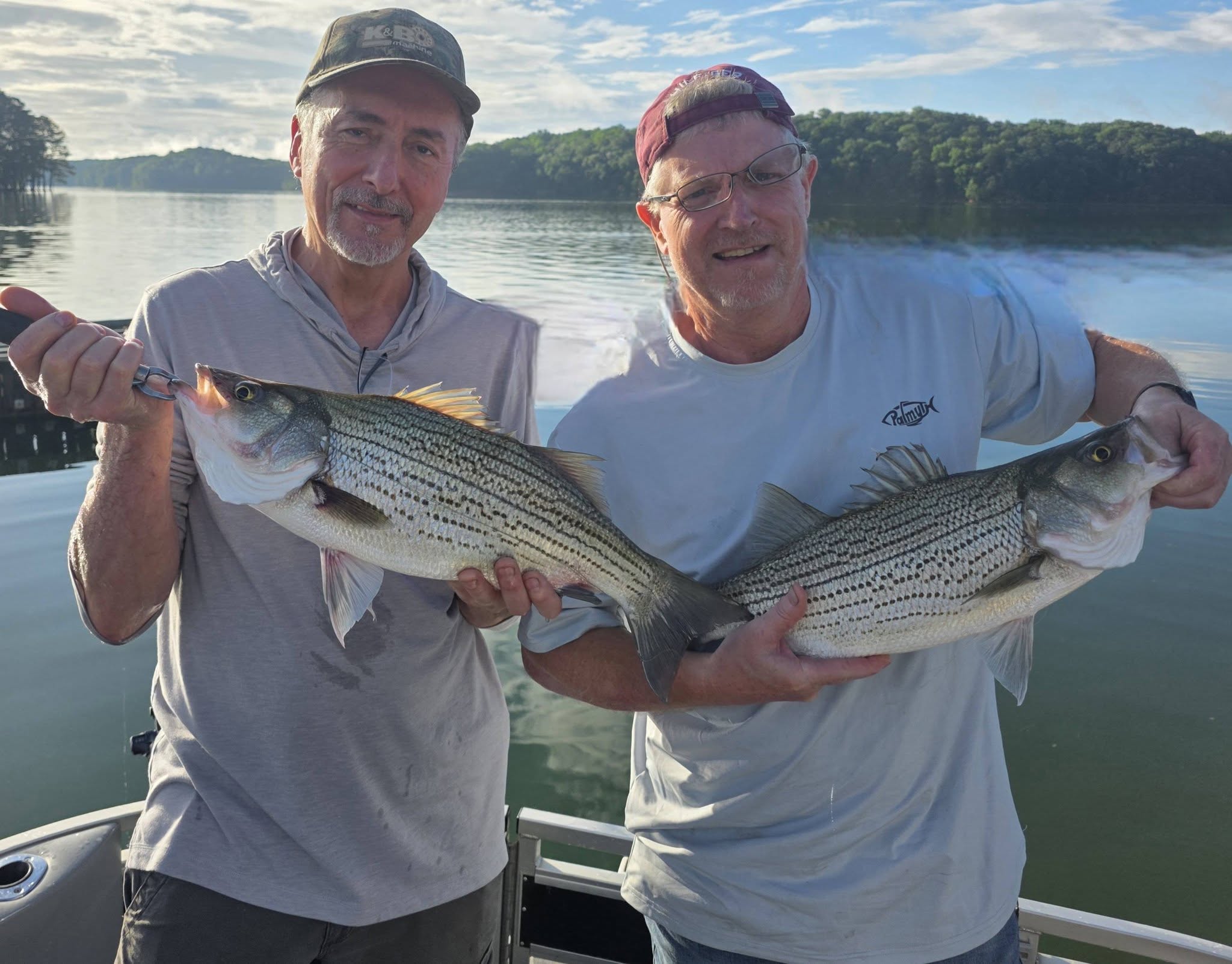 Two anglers holding striped bass catch on boat in Acworth GA lake