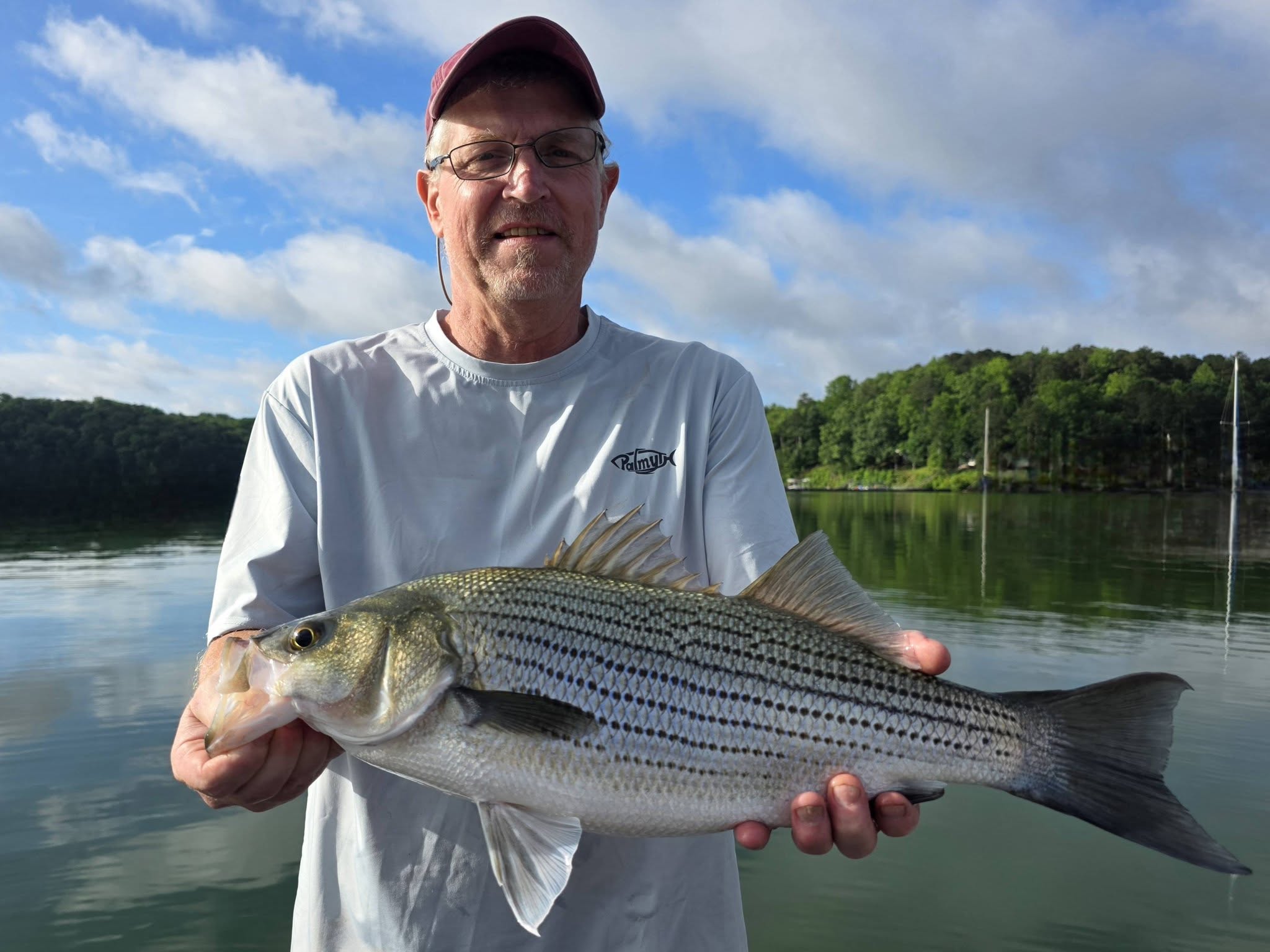 Angler holding freshly caught striped bass on lake in Acworth GA