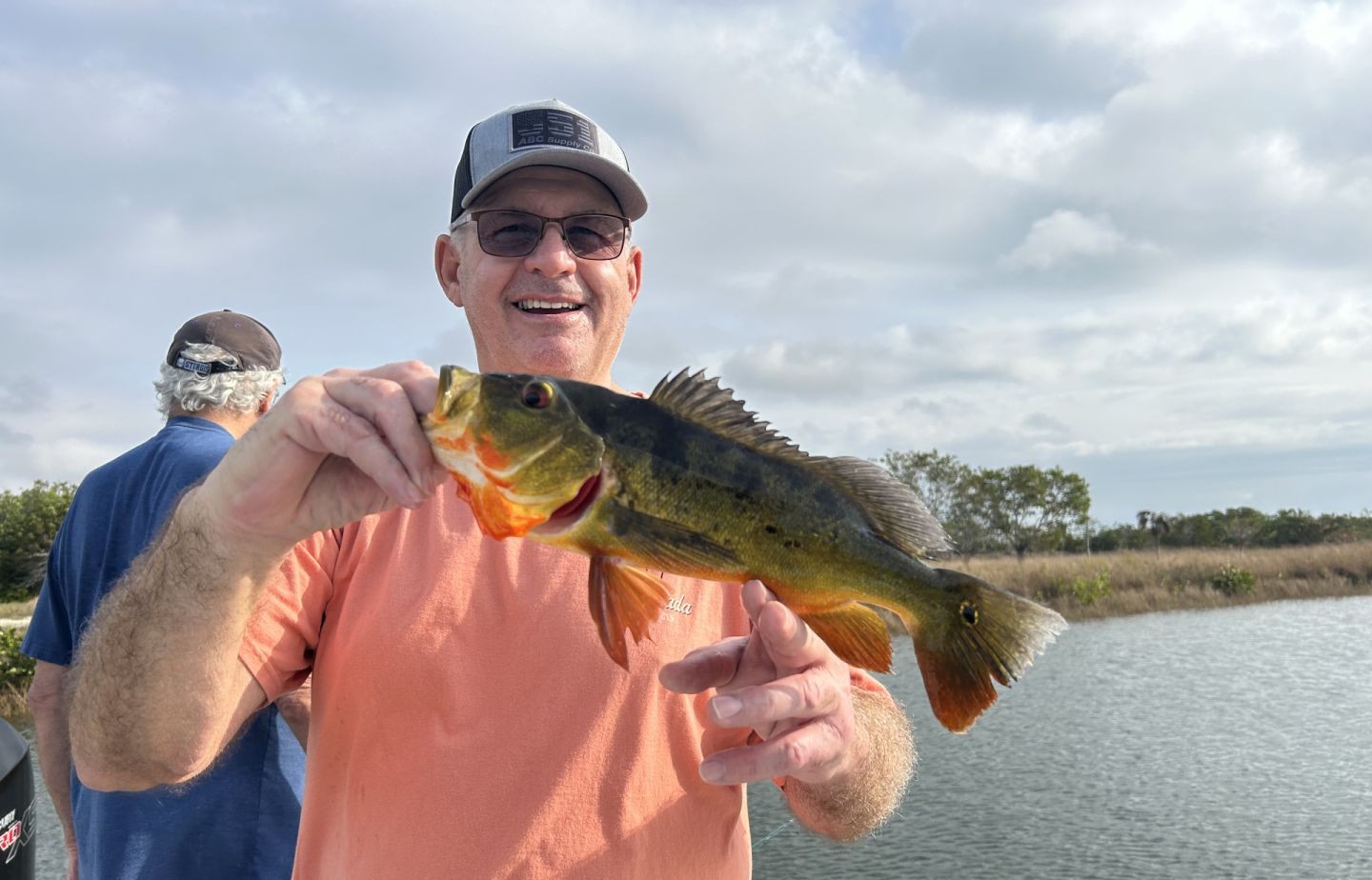 Angler holding freshly caught peacock bass while fishing in Palmetto Bay FL