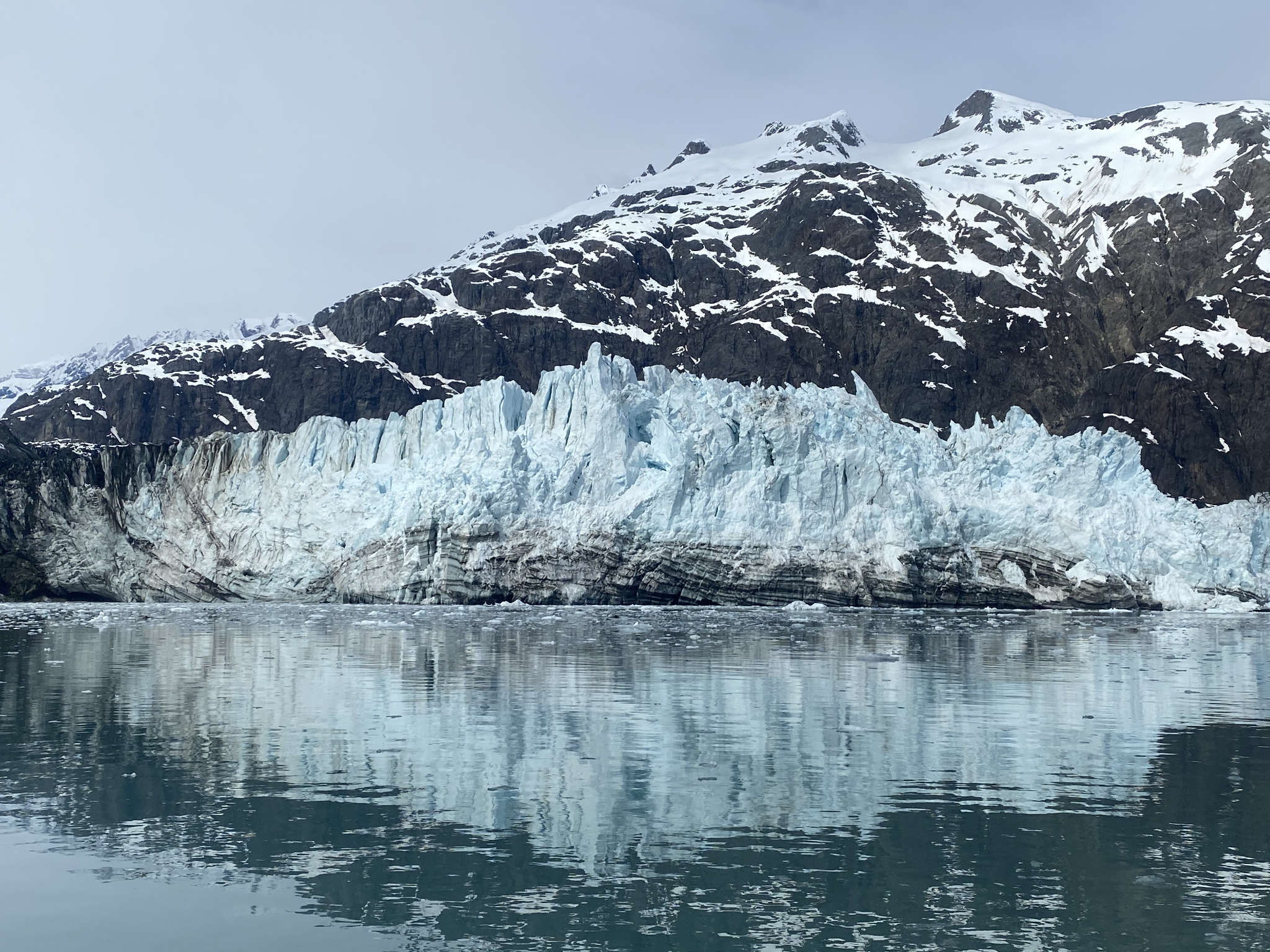 Glacier and snow-covered mountains reflected in calm waters in Juneau Alaska