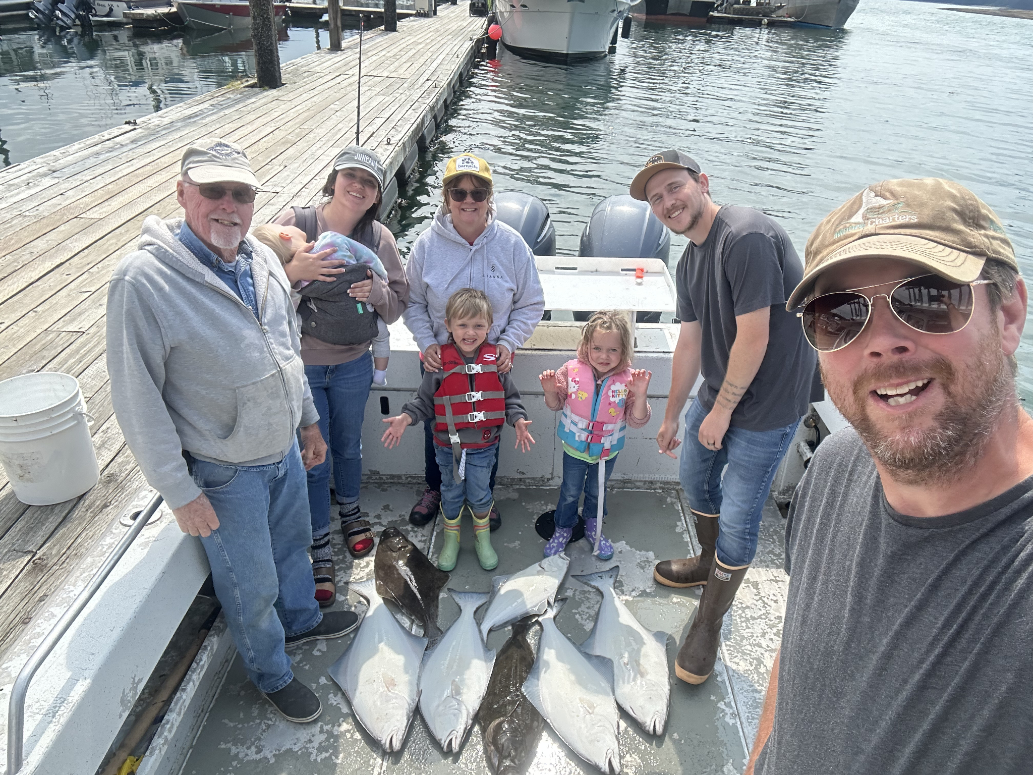 Family fishing trip in Juneau Alaska with fresh caught salmon on boat deck at marina