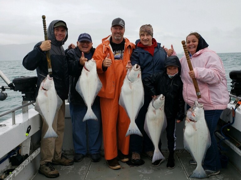 Shared halibut fishing charter boat in Juneau Alaska waters with mountain backdrop