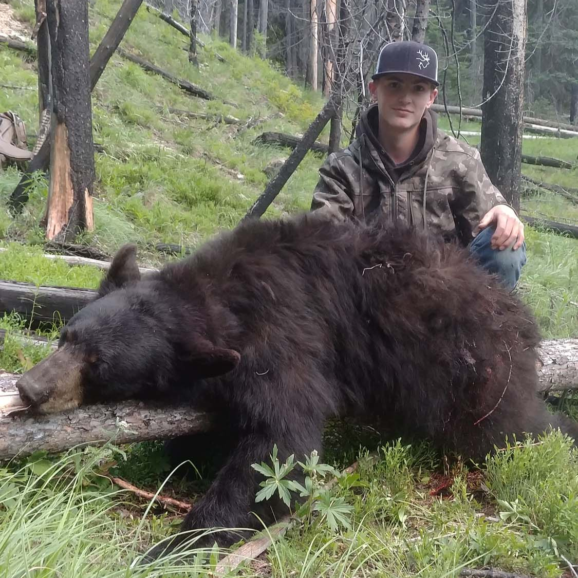 Wyoming fall black bear hunting guide with rifle in wilderness terrain