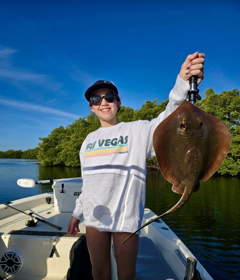 Stingray catch held up on fishing boat in St. Petersburg FL waters with mangroves in background