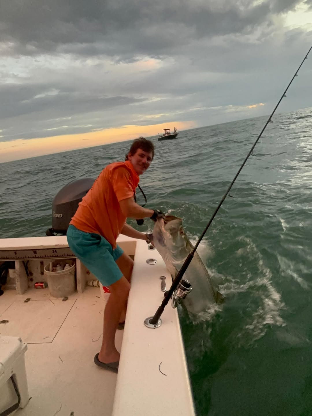 Fishing charter boat with angler reeling in catch on ocean waters near Holmes Beach FL