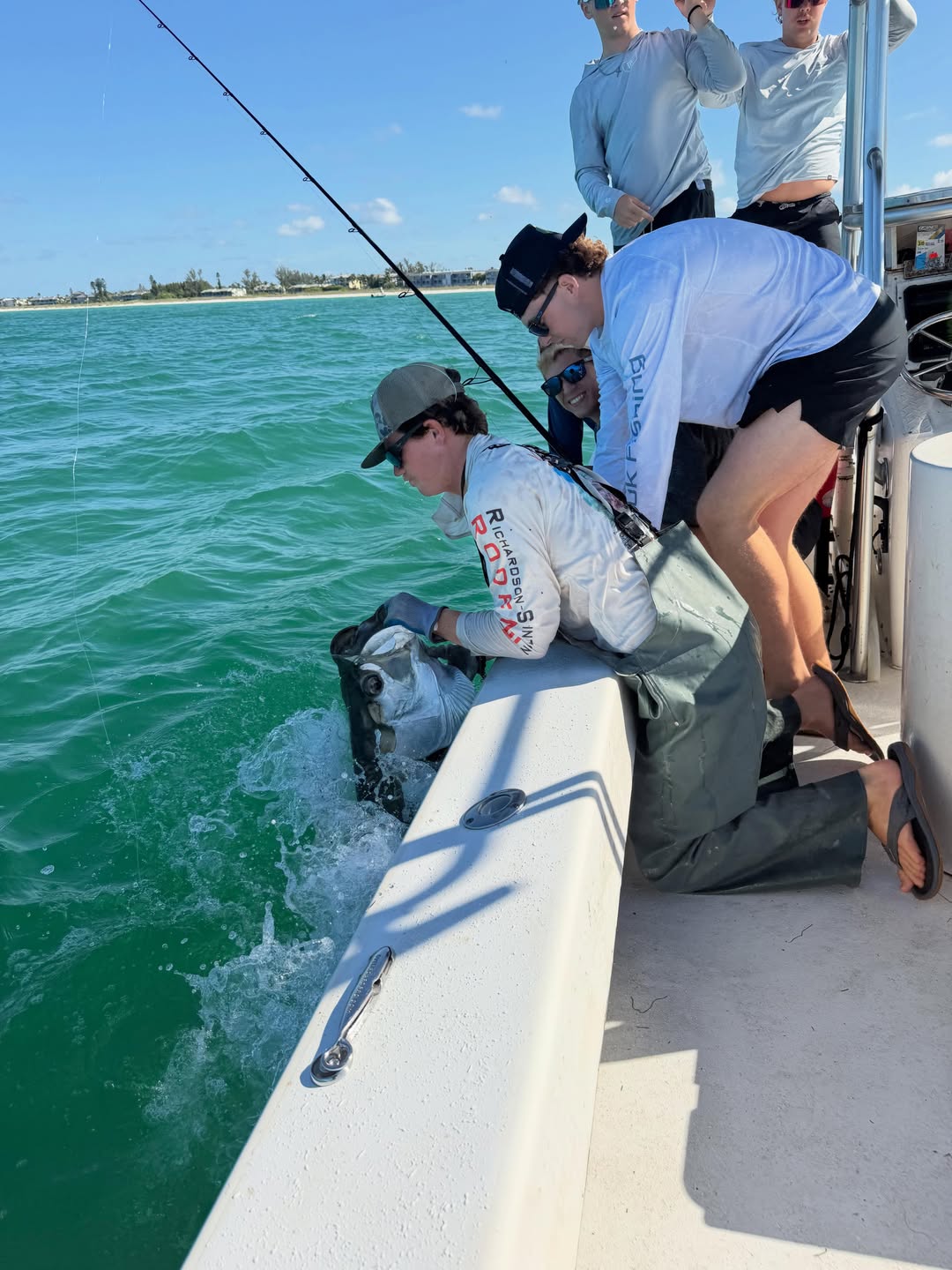 Fishing charter in Holmes Beach FL with angler fighting fish from boat in turquoise waters