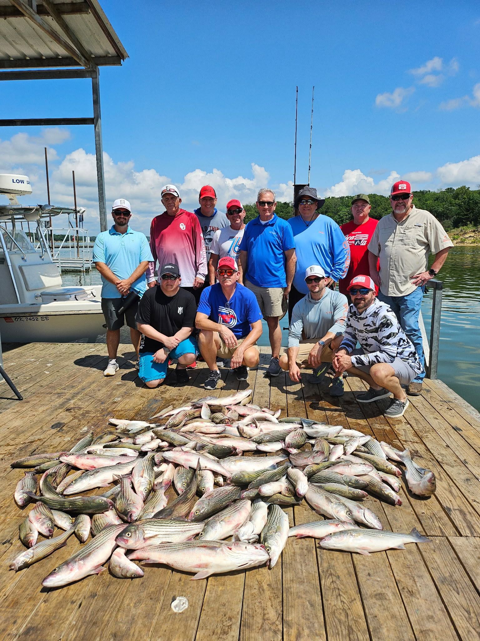 Large catch of striped bass displayed on wooden dock after successful fishing trip in Kingston OK