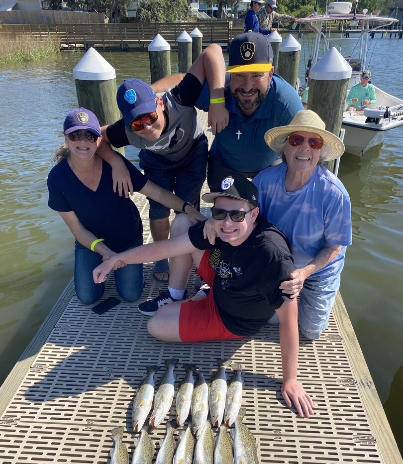 Fishing group with fresh caught speckled trout on dock in Gulf Shores AL