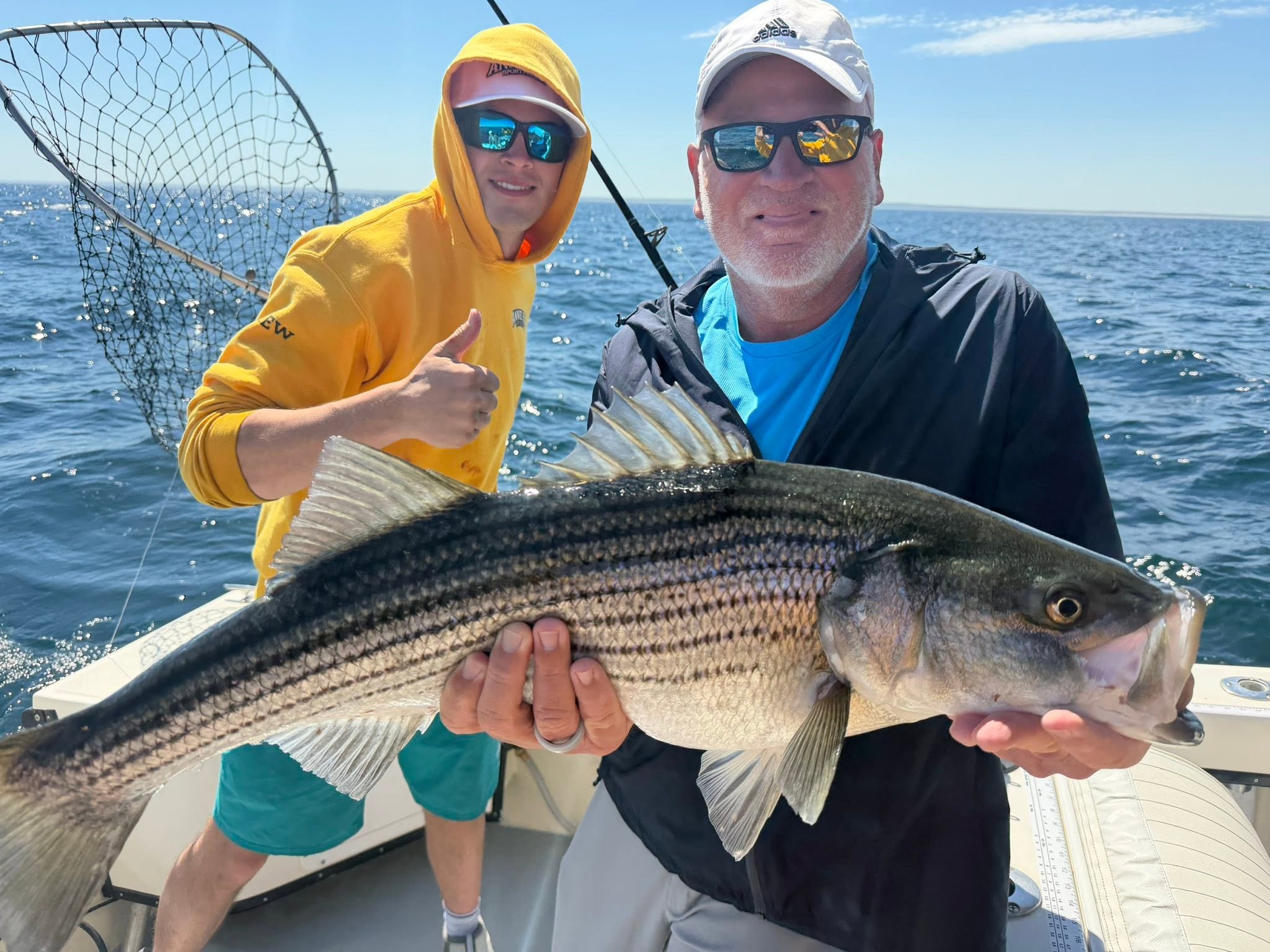 Striped bass caught during fishing charter in Barnstable MA with boat and ocean background