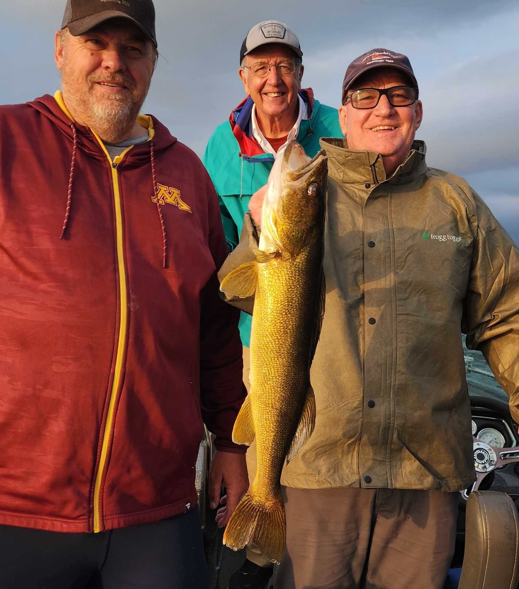 Three anglers displaying a caught walleye fish during fishing trip in Breezy Point Minnesota