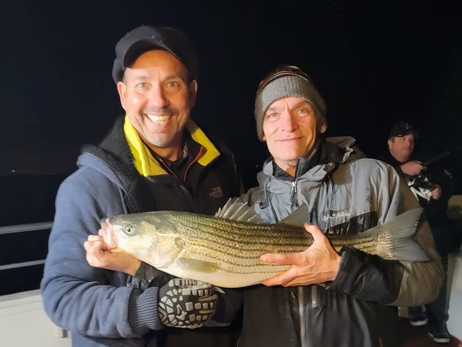 A fisherman holding a white bass fish in Keyport