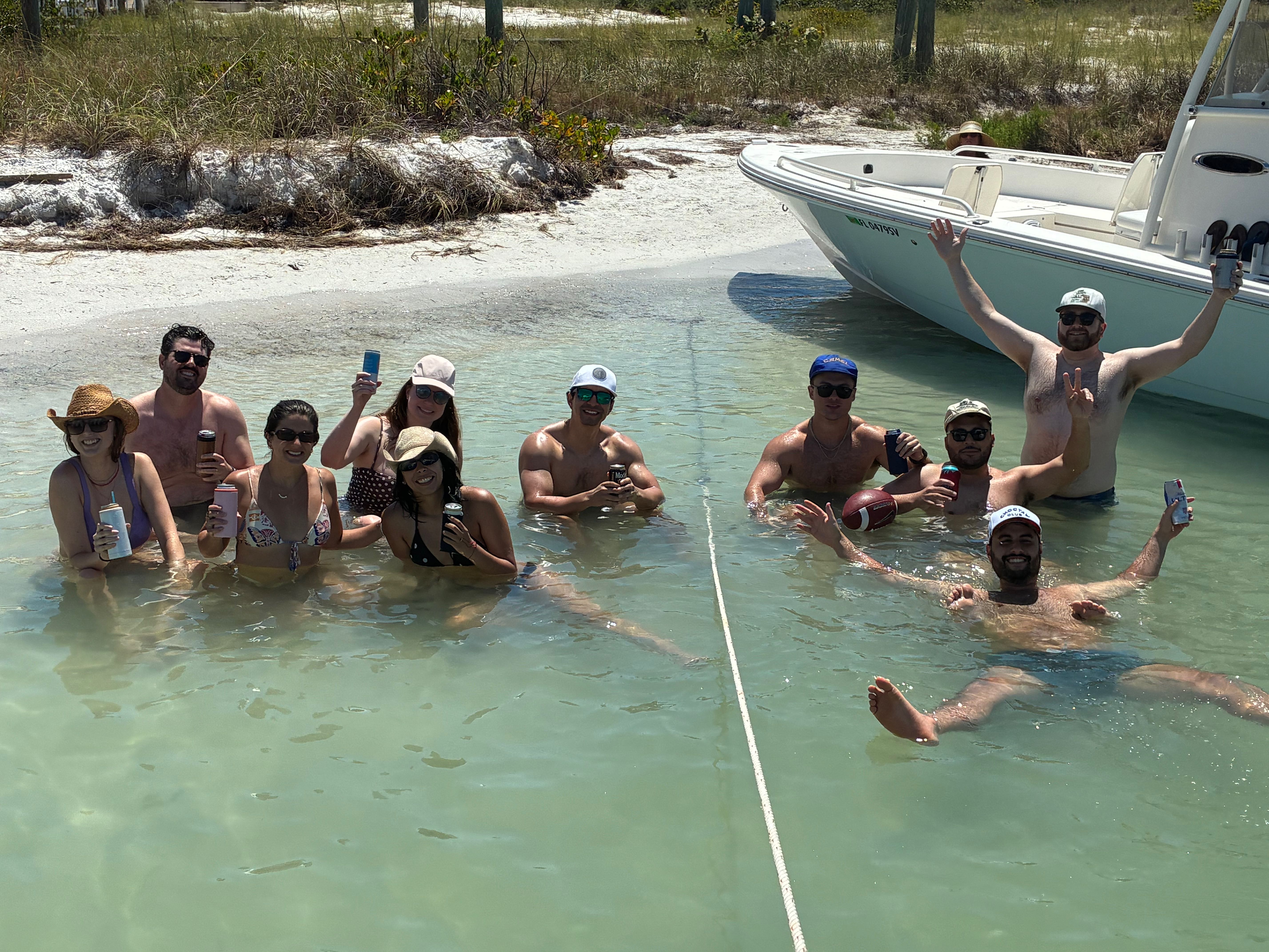Group enjoying water activities in clear shallow waters near beached boat in St. Petersburg FL