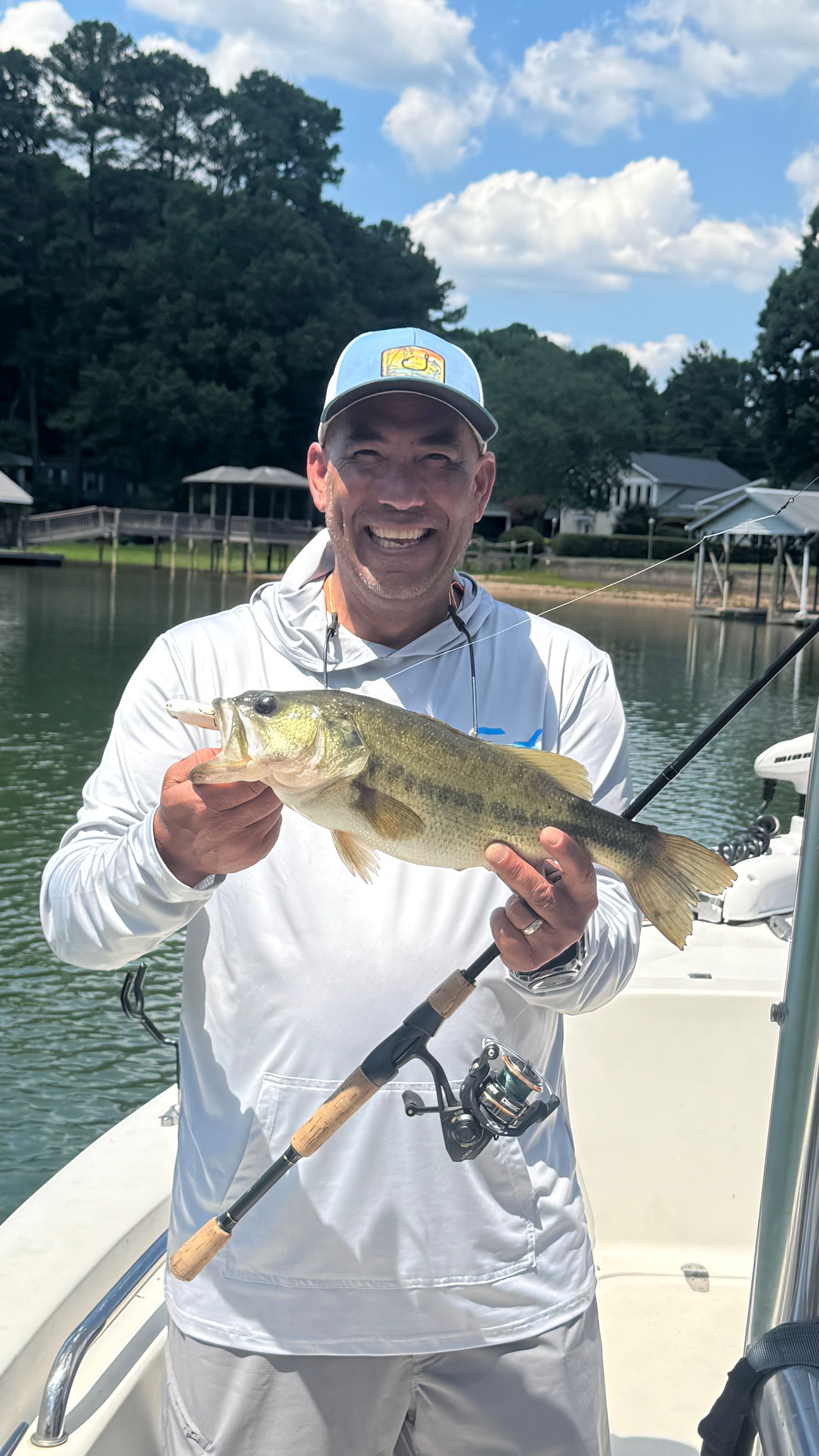 Freshly caught bass held on fishing boat in Denver NC lake with wooded shoreline